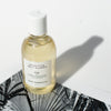 Detoxifying Daily Cleanser bottle with gold color liquid casting a shadow on top of black and white photograph