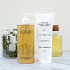 Botanical Protein Complex Shampoo and conditioner with beaker of rosemary and jar of yellow oil behind them
